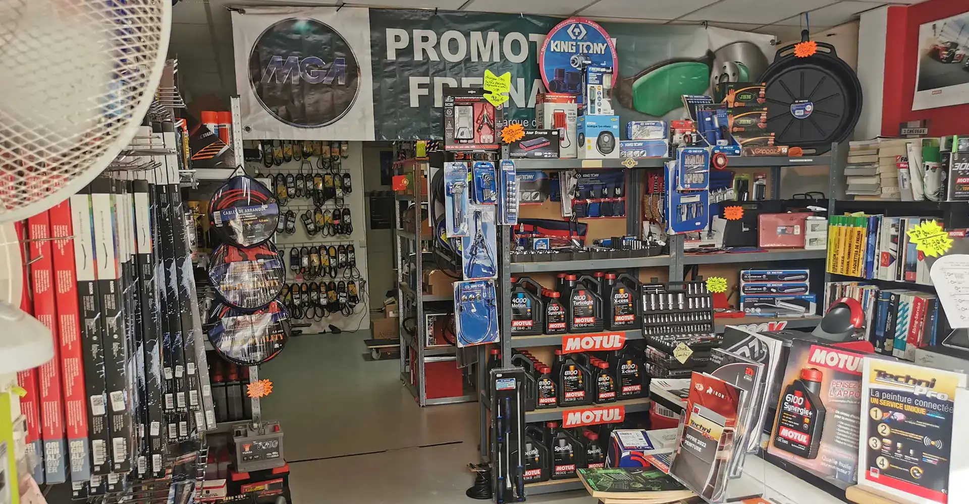 Rayons d'un magasin auto avec huile Motul, outils King Tony et bannière Promotion Freinage.
